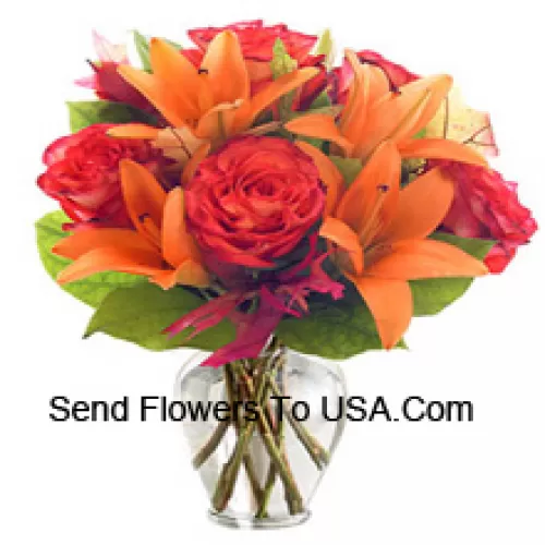Orange Lilien und Orange Rosen mit saisonalen Füllstoffen, wunderschön in einer Glasvase arrangiert
